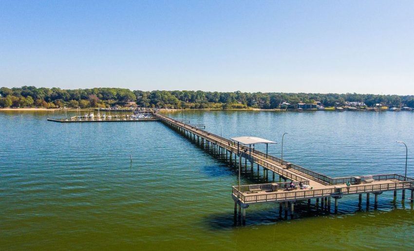 Waterfront pier with boats and greenery, ideal for Magnolia Springs Alabama travel blog.